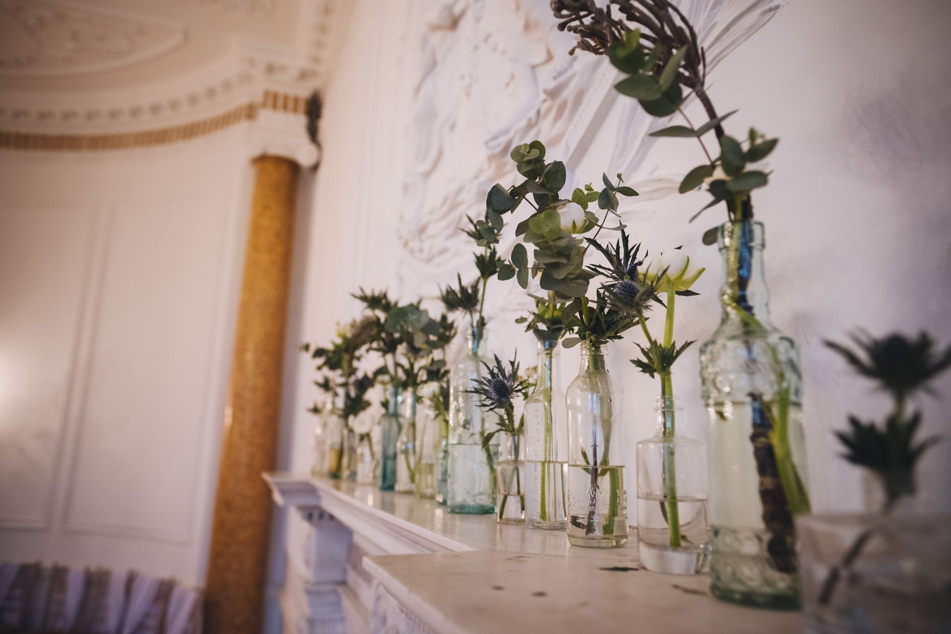 a row of vases filled with flowers are sitting on a mantle.