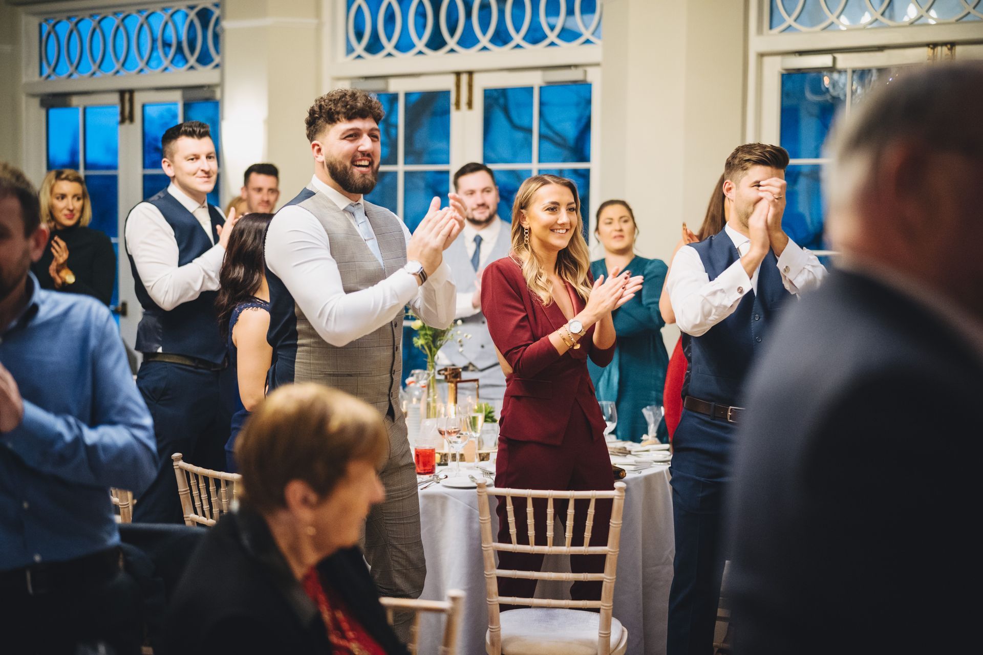 a group of people are clapping their hands at a wedding reception.