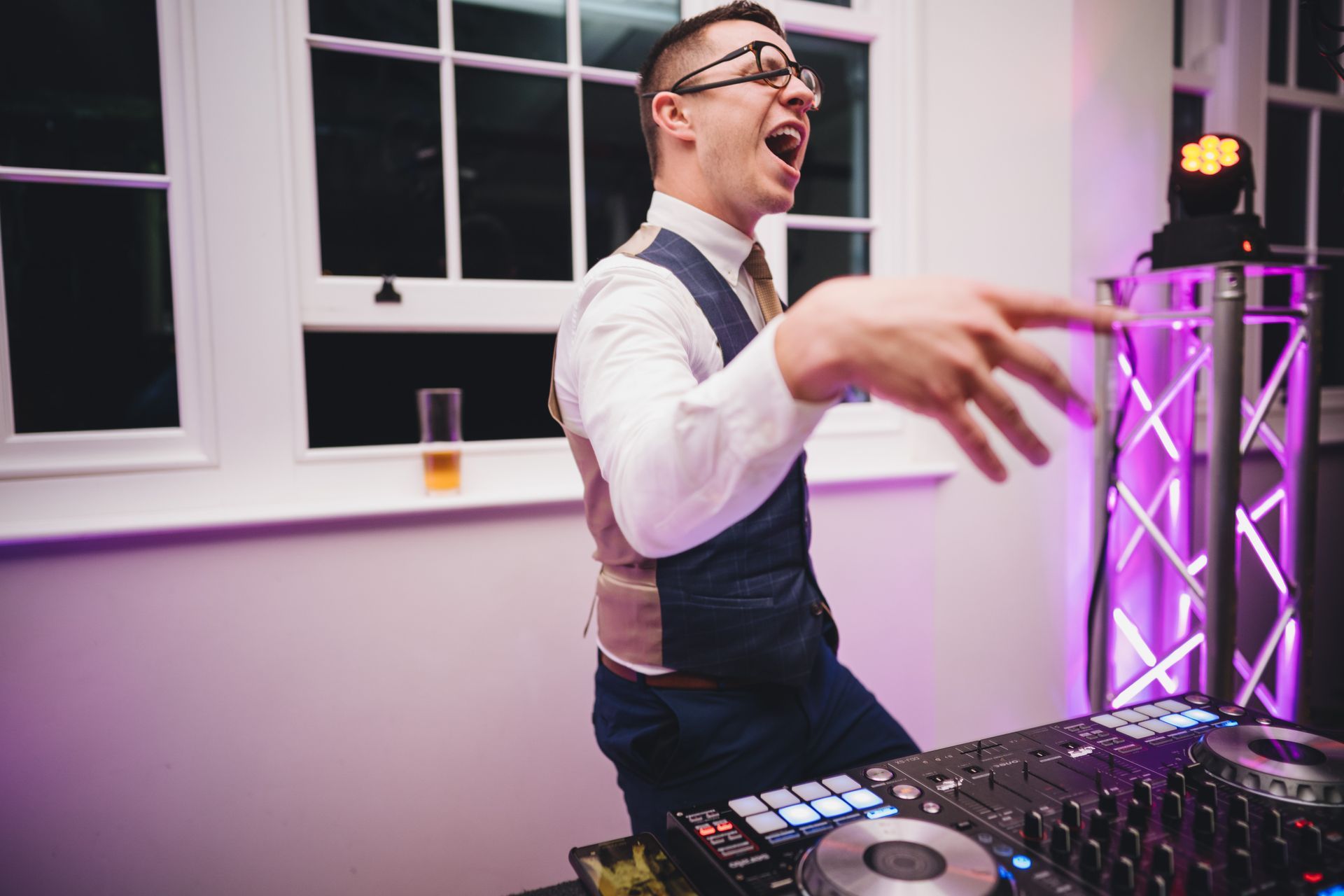a man in a suit and tie is standing in front of a dj mixer .