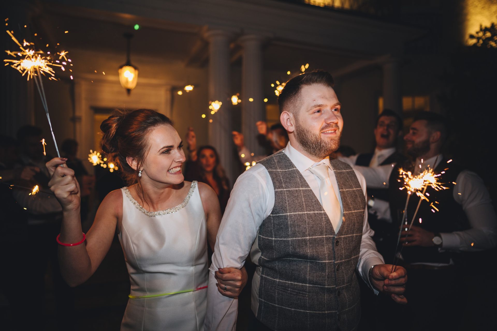 a bride and groom are walking through a crowd of people holding sparklers.