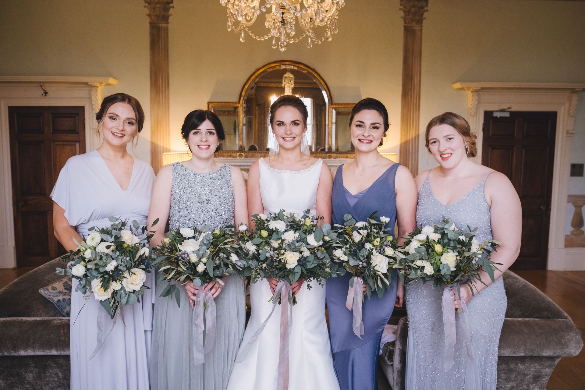a bride and her bridesmaids are posing for a picture while holding bouquets of flowers .