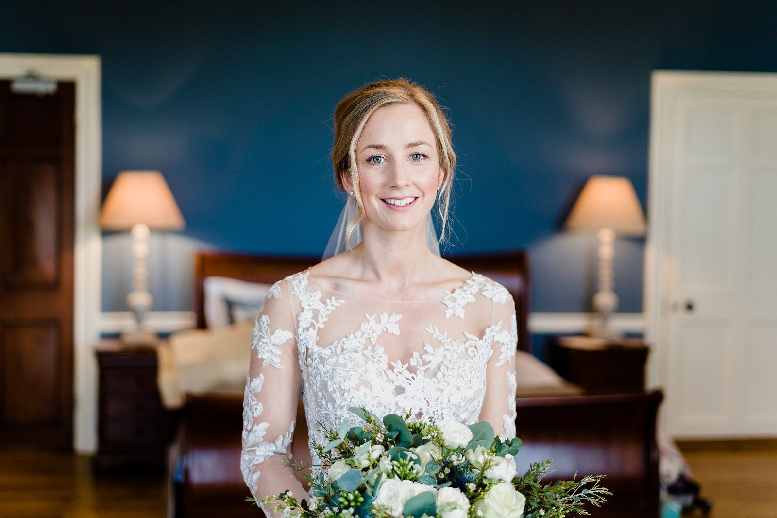 a bride in a wedding dress is holding a bouquet of flowers in a bedroom .