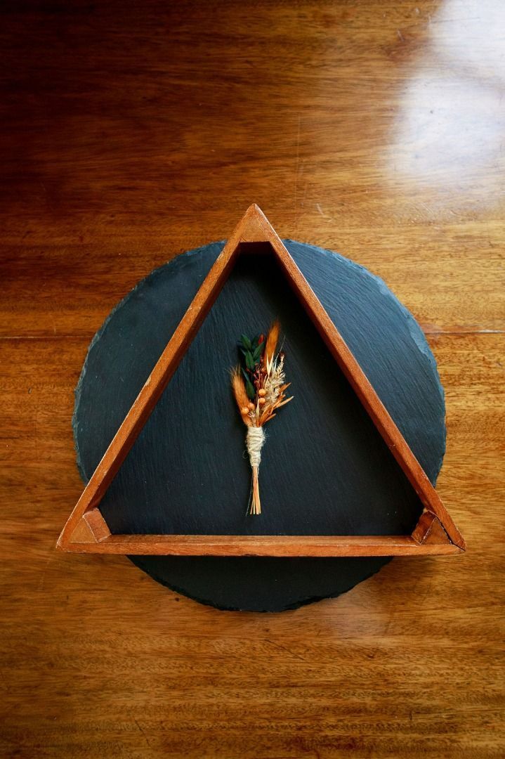a triangle shaped tray with a flower in it on a wooden table.