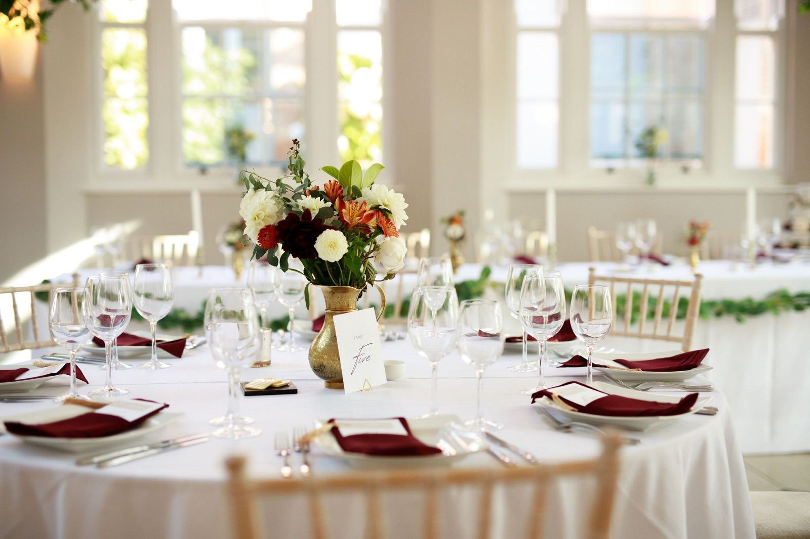a table set for a wedding reception with a vase of flowers on it.
