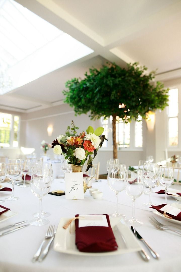 a table set for a wedding reception with a tree in the background
