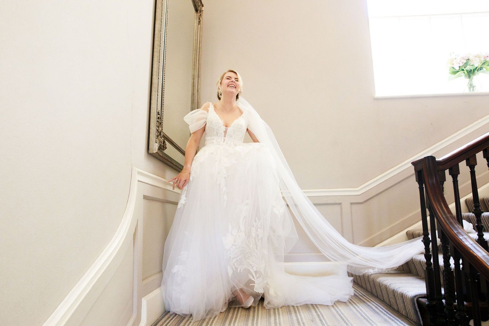 a bride in a wedding dress and veil is walking down a set of stairs.