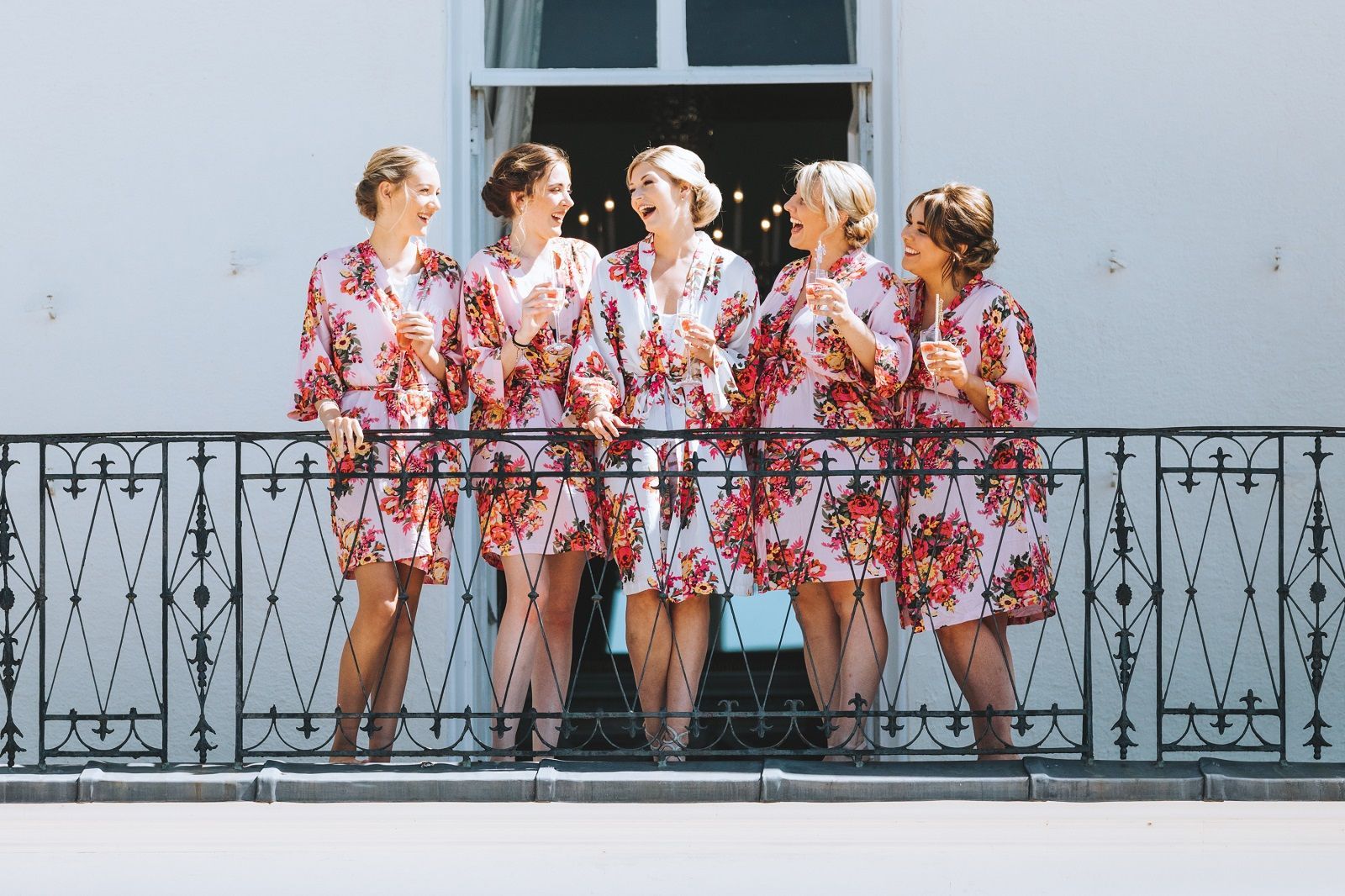 a group of women are standing on a balcony drinking champagne .