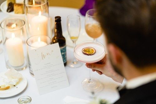 a man is holding a cocktail in his hand at a table .