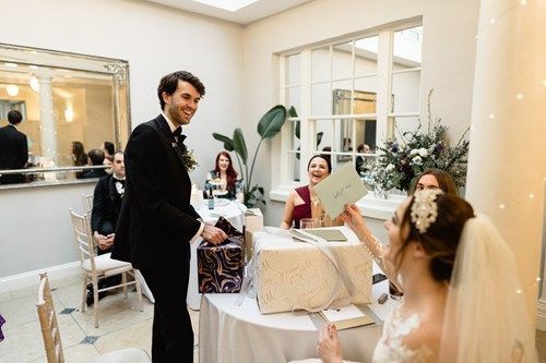 a bride and groom are opening a gift box at their wedding reception .