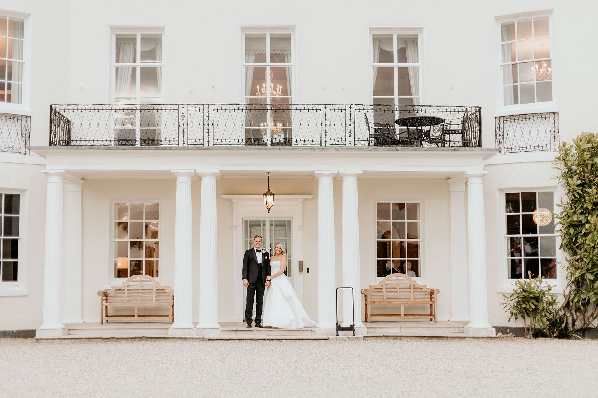 a bride and groom are standing in front of a large white building .