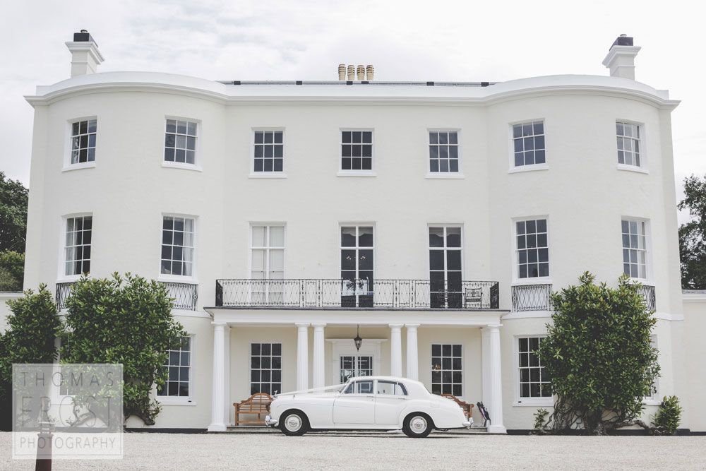 a white car is parked in front of a large white building