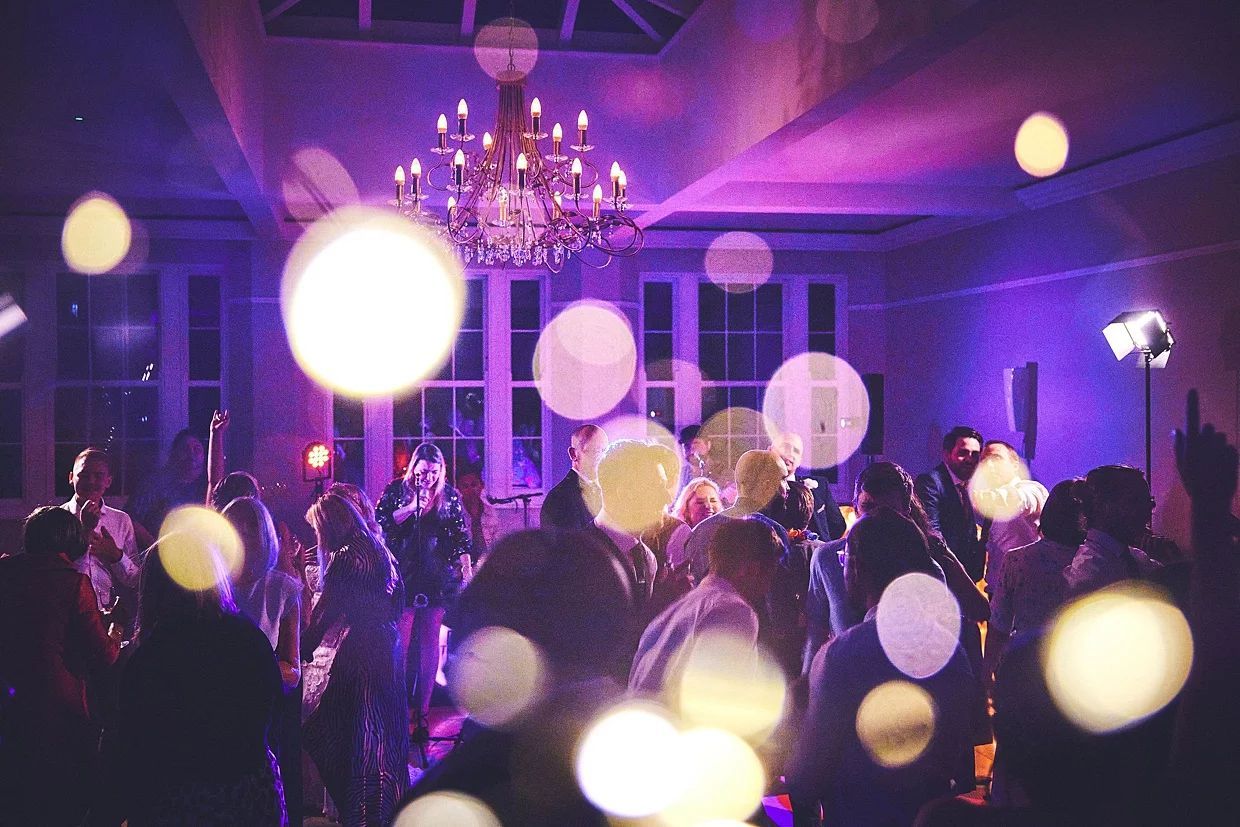 a group of people are dancing in a room with purple lights .