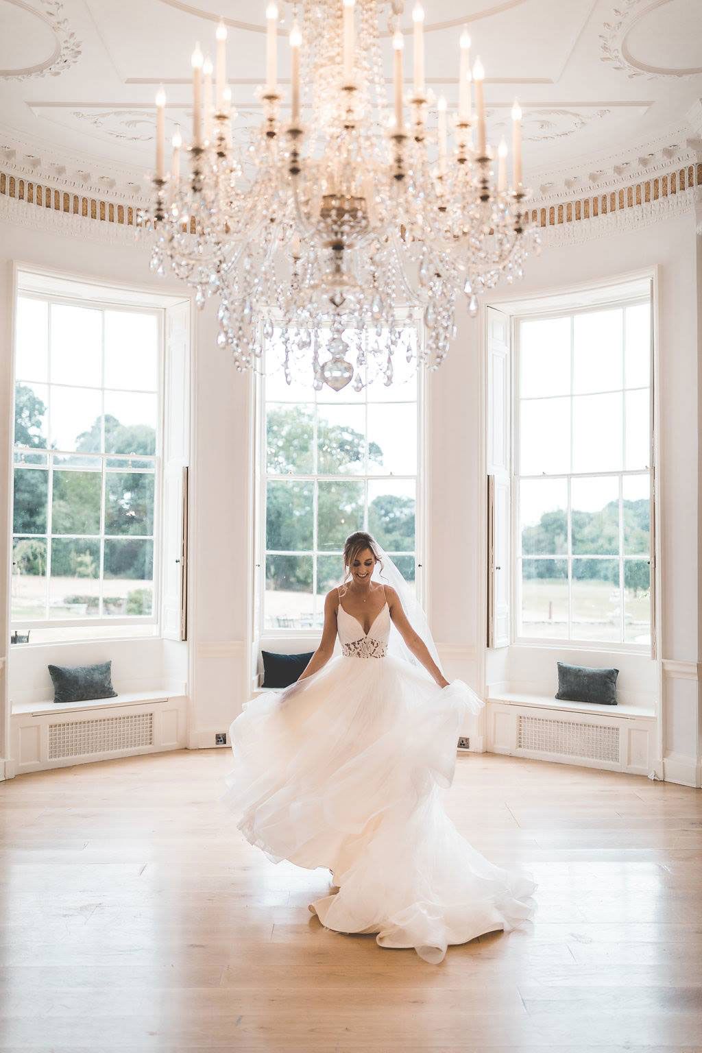 a bride in a wedding dress is standing in a room under a chandelier .
