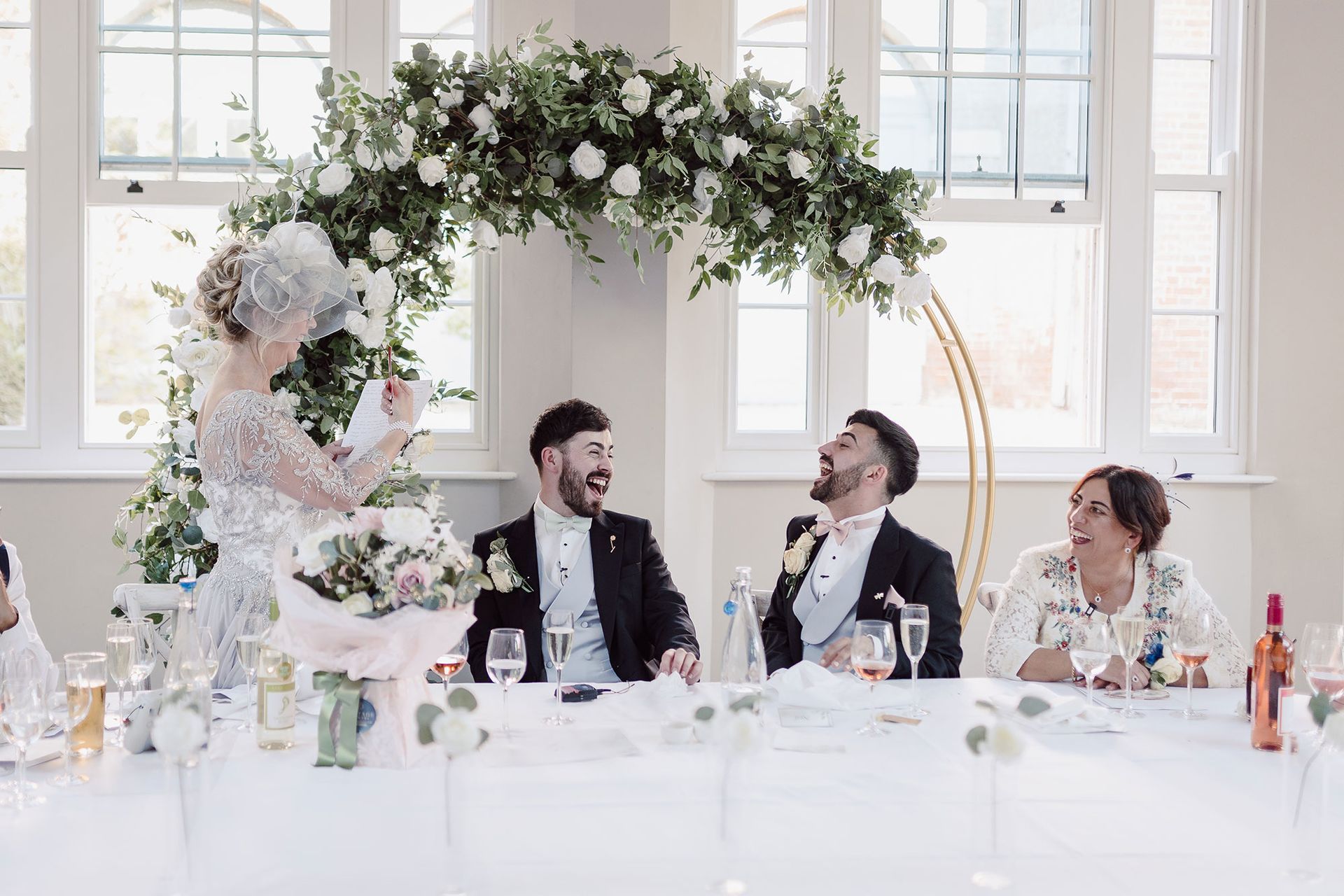 two men are sitting at a long table at a wedding reception .