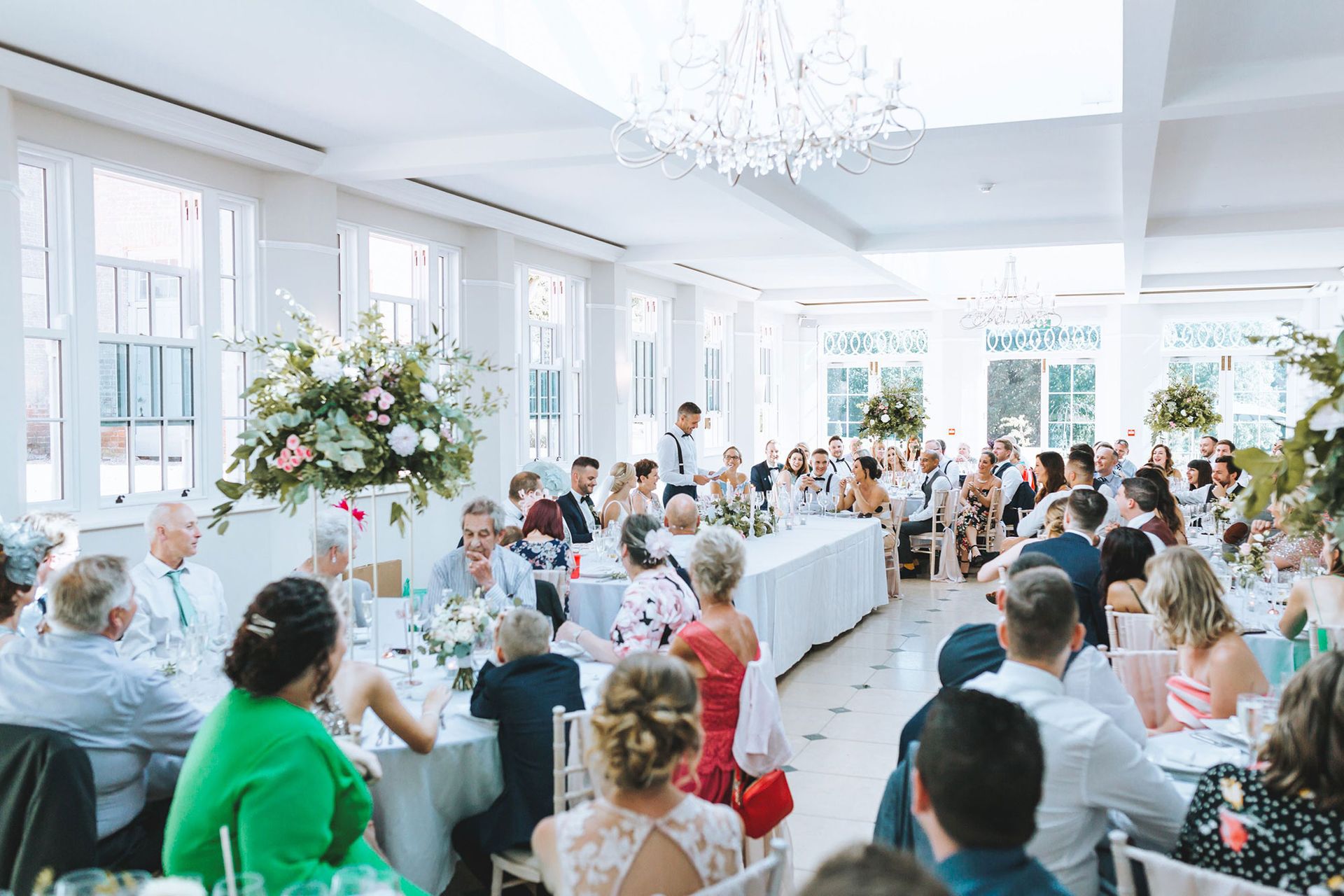 a large group of people are sitting at tables at a wedding reception.