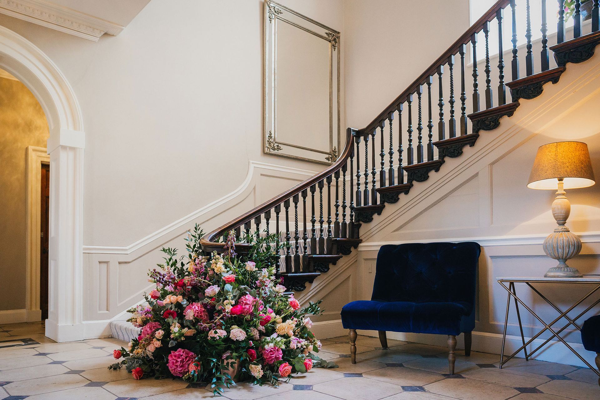 a staircase with a chair and a vase of flowers in front of it .