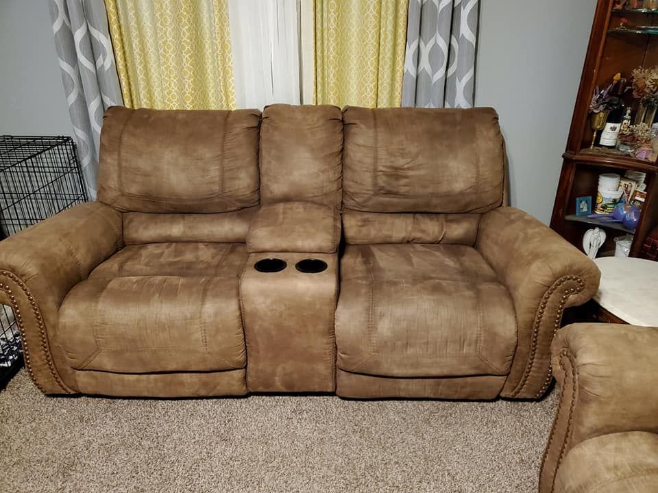 A brown couch is sitting in a living room next to a window.