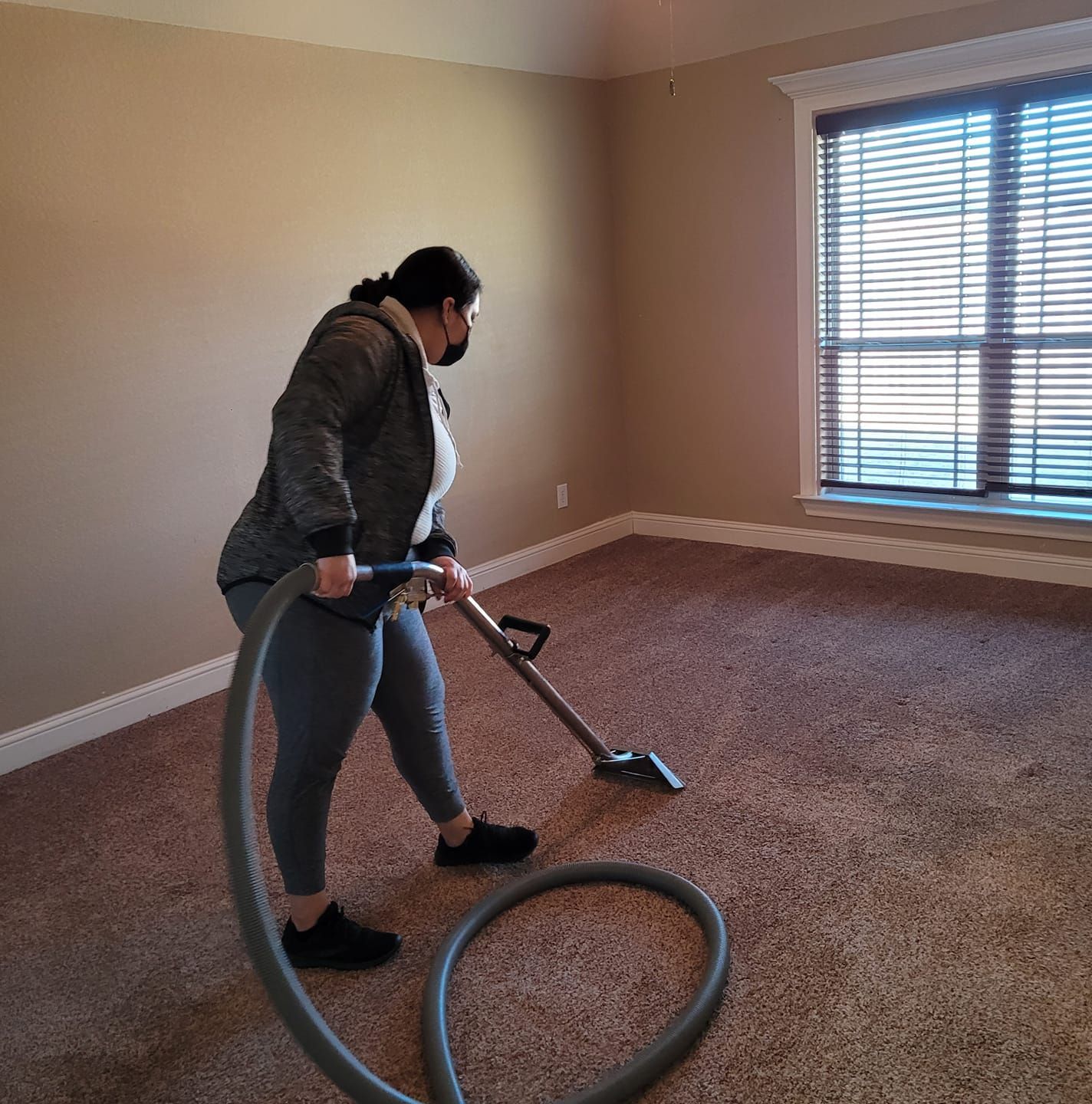 A woman is using a vacuum cleaner in an empty room