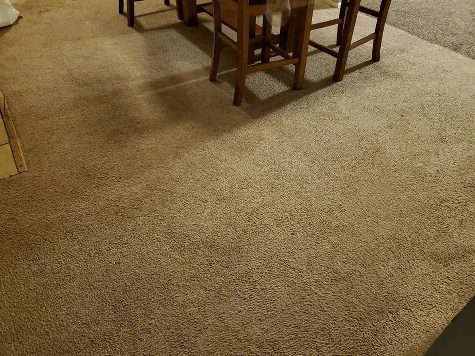 A carpeted floor with a table and chairs on it.