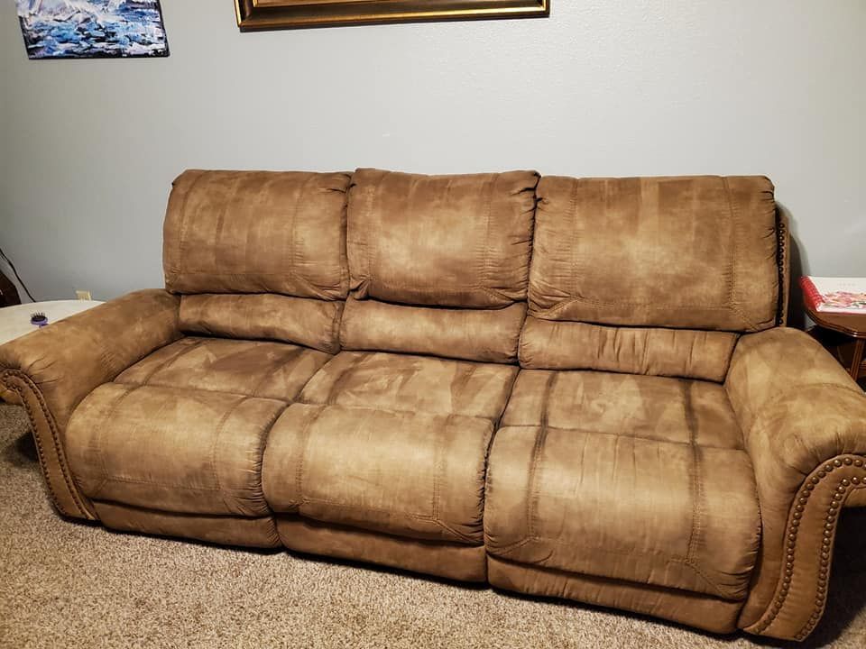 A brown recliner couch is sitting in a living room next to a table.