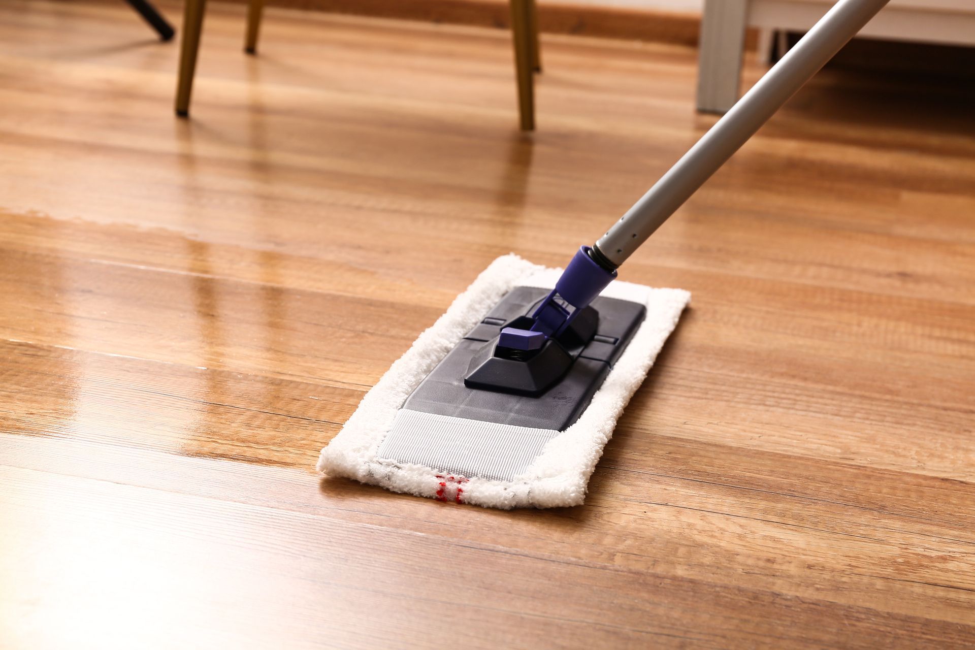 A person is cleaning a wooden floor with a mop.