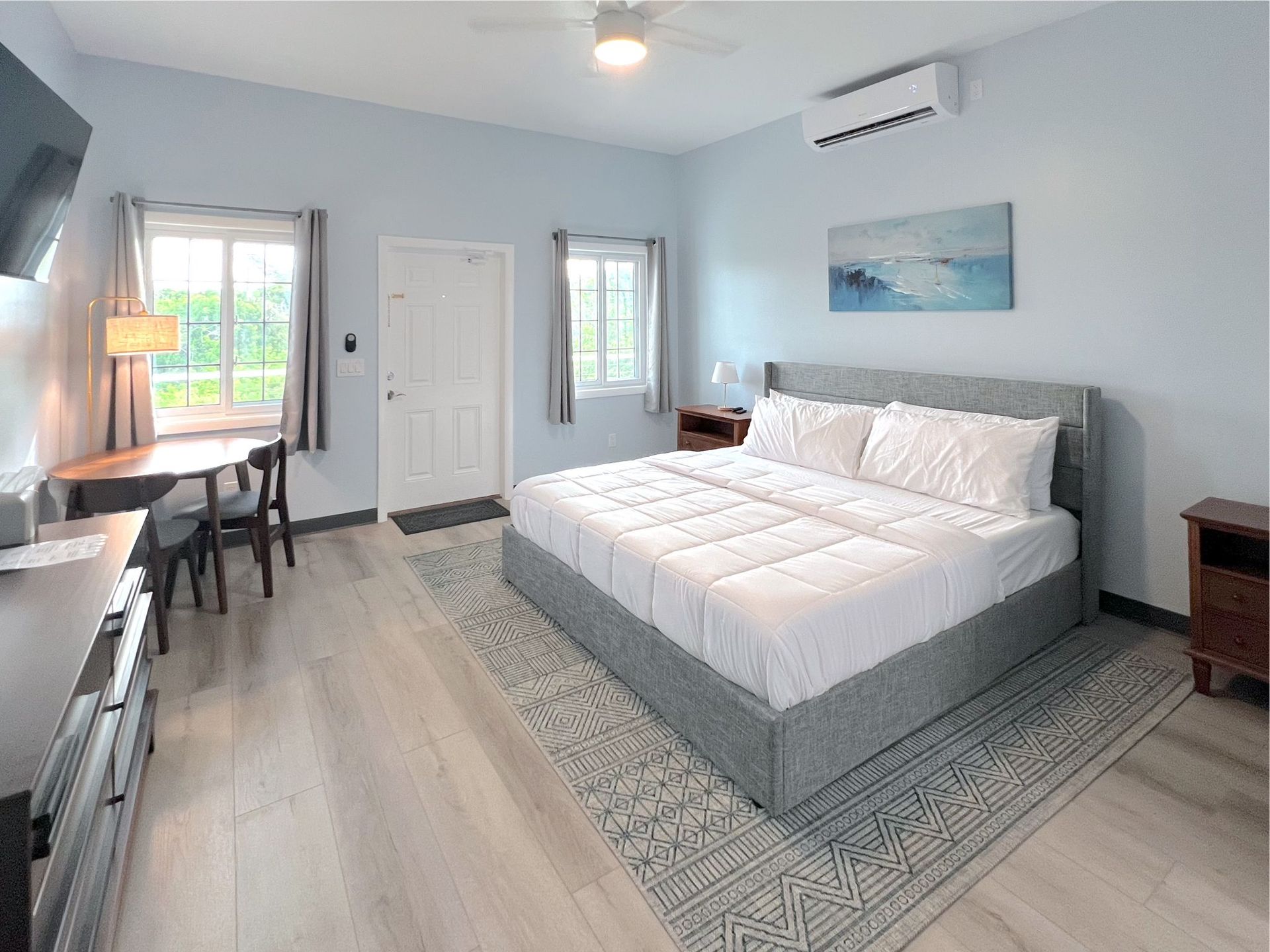 Bedroom with a large bed, desk, and a light blue wall.