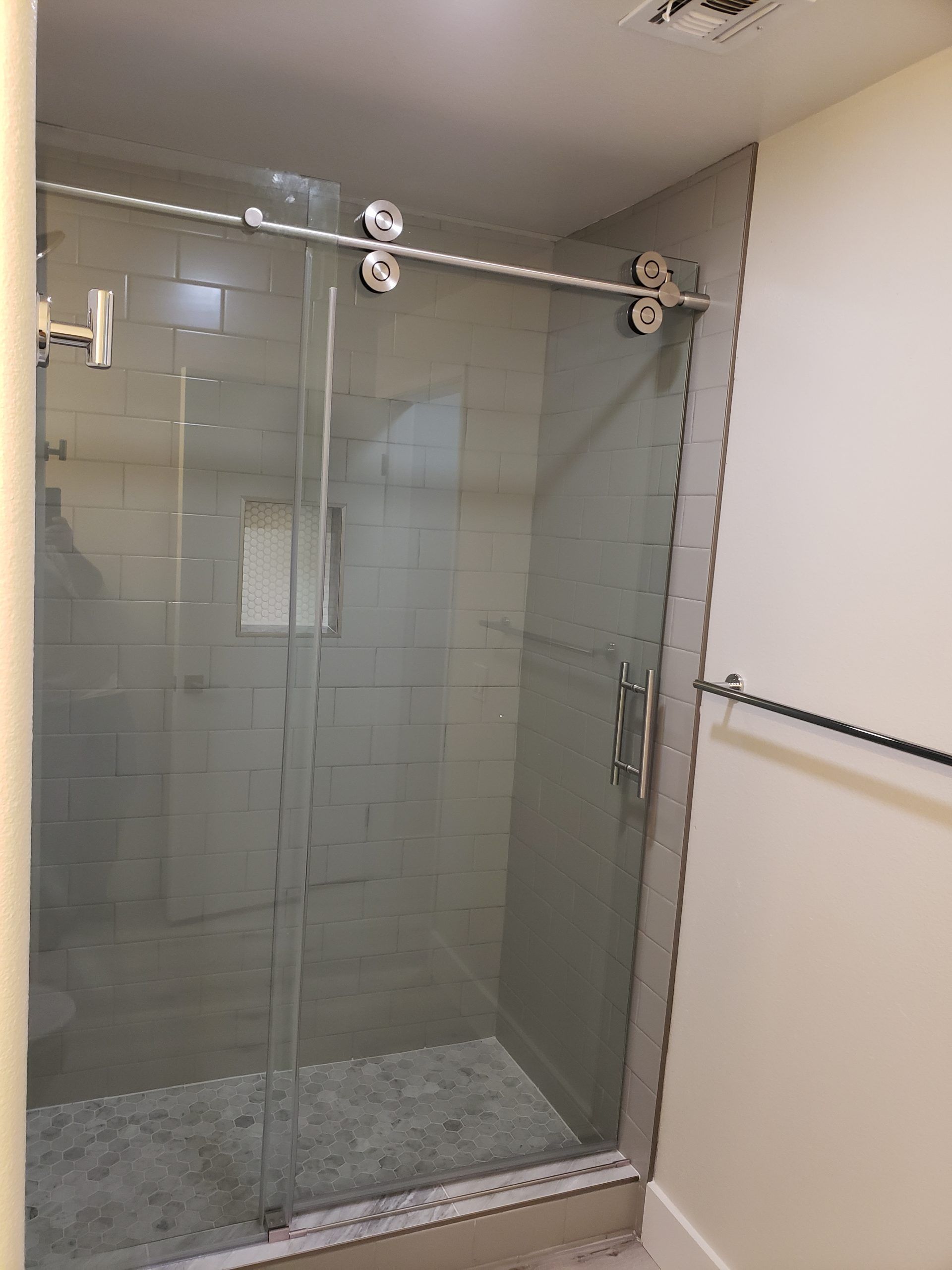 A bathroom with a sliding glass shower door from a Bathroom remodel in San Diego CA by Team Renovate