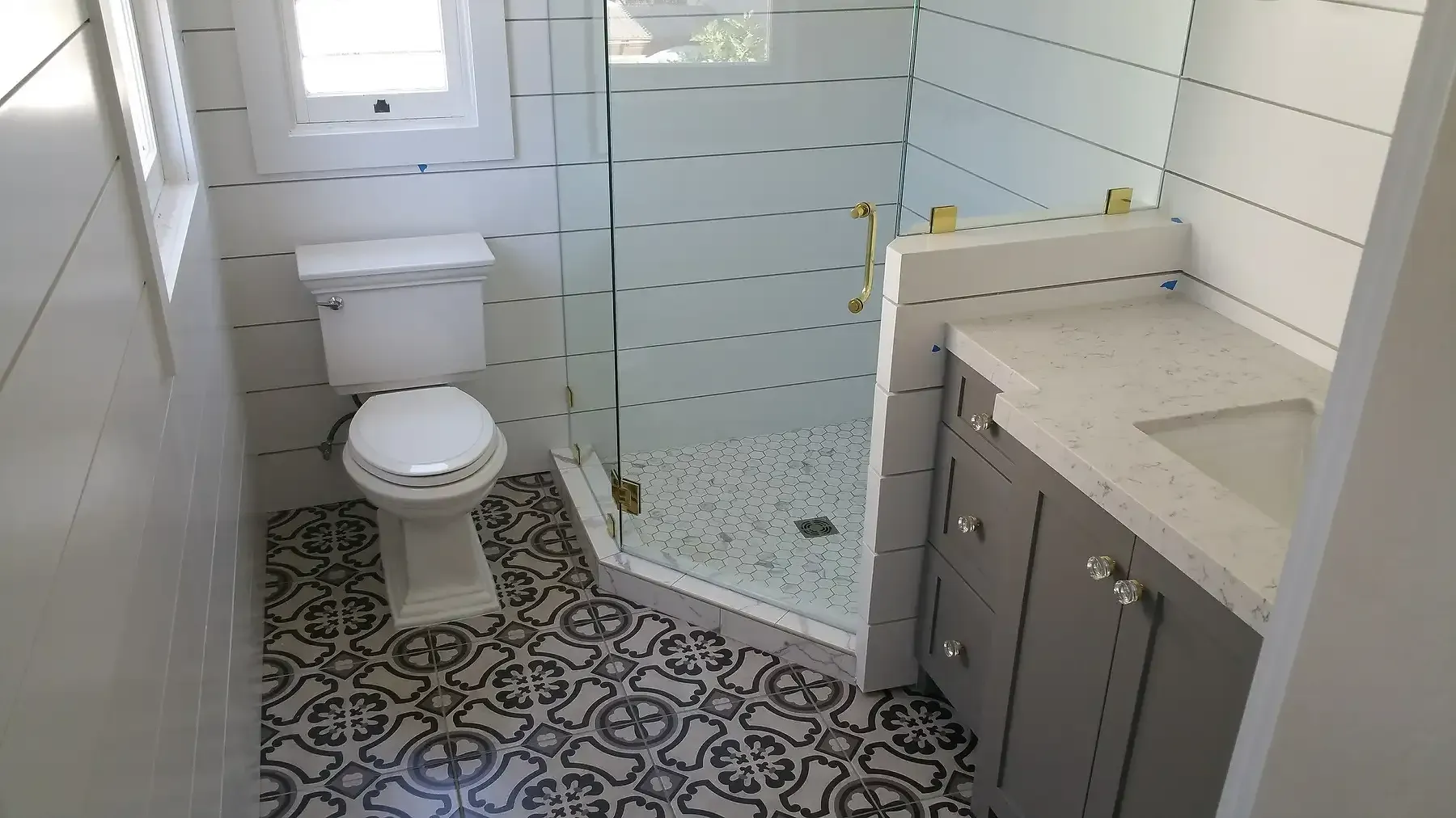 A bathroom with a toilet , sink and shower. Bathroom remodel  with gold accents in Point Loma
