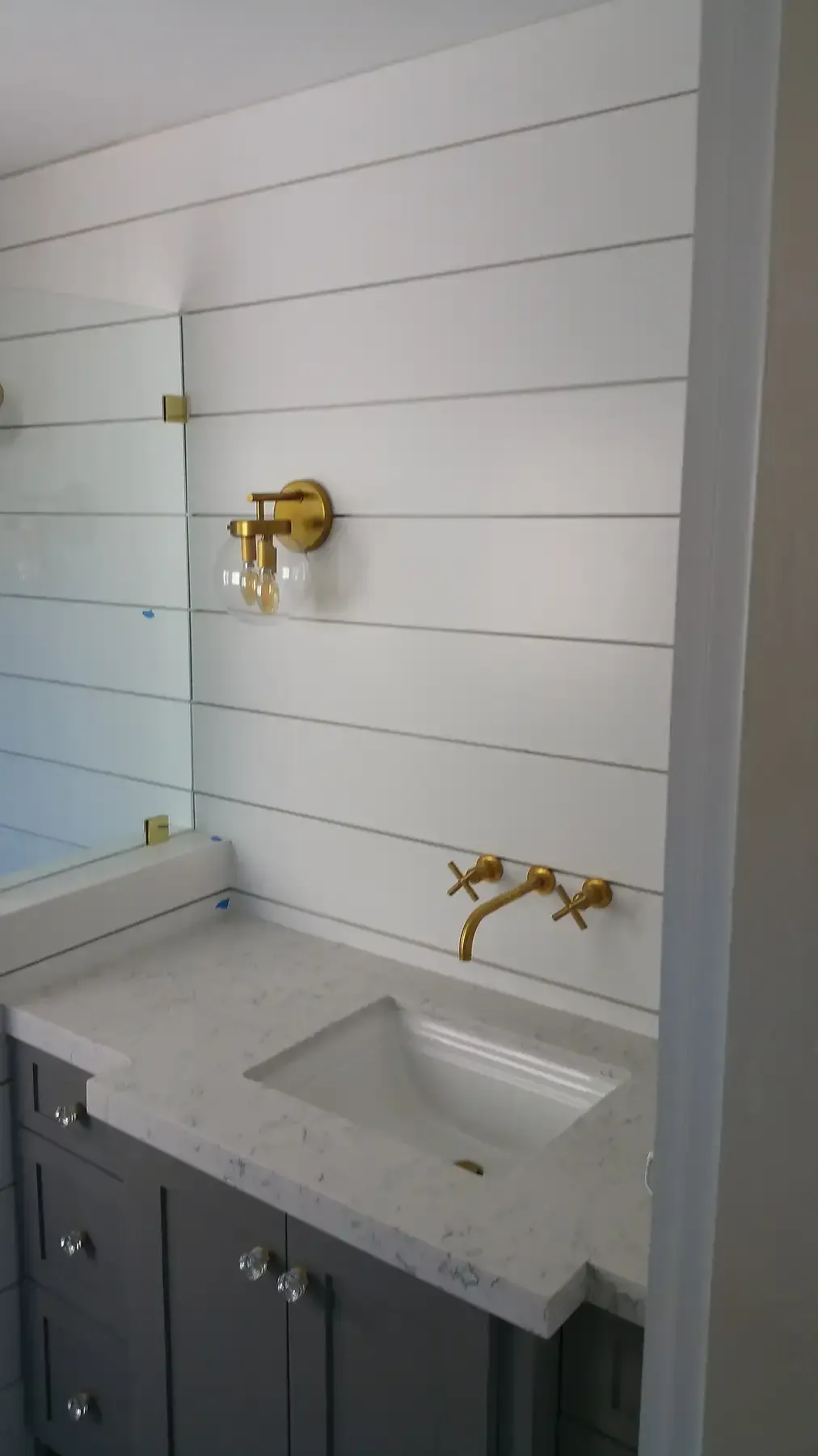 A bathroom with a sink , mirror and faucet. Bathroom remodel  with gold accents in Point Loma