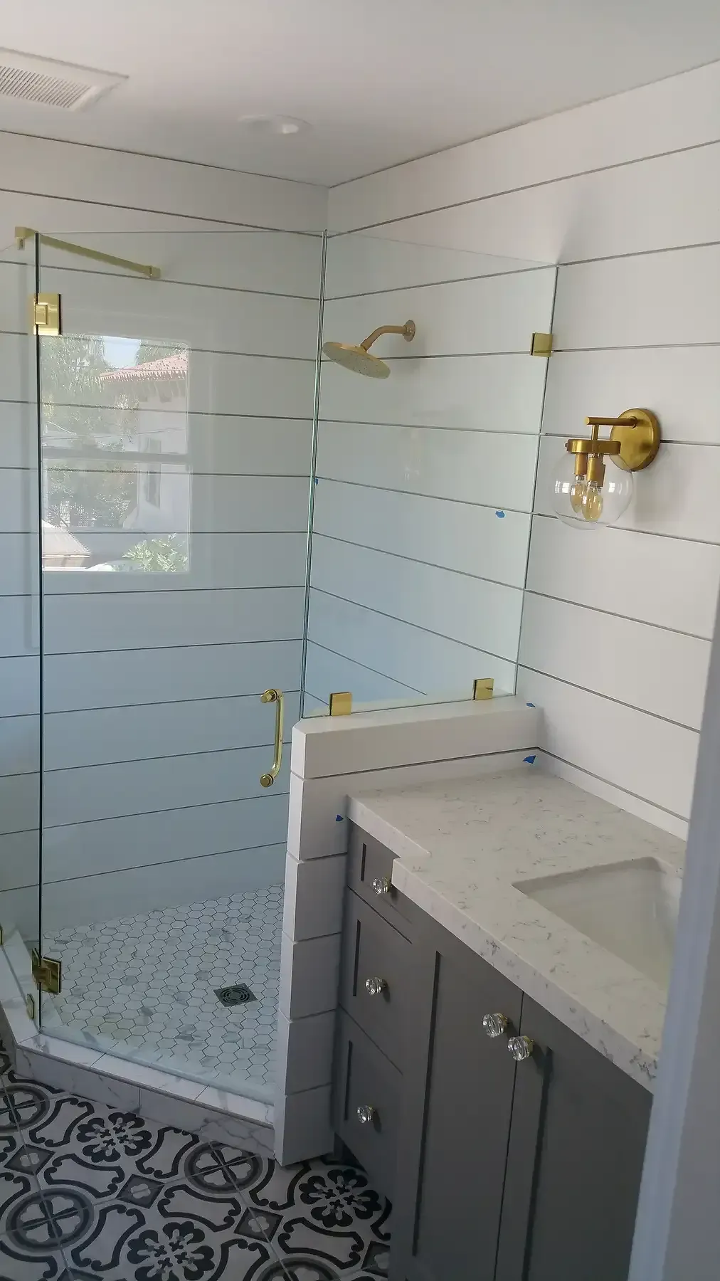 A bathroom with a walk in shower , sink and mirror. Bathroom remodel  with gold accents in Point Loma