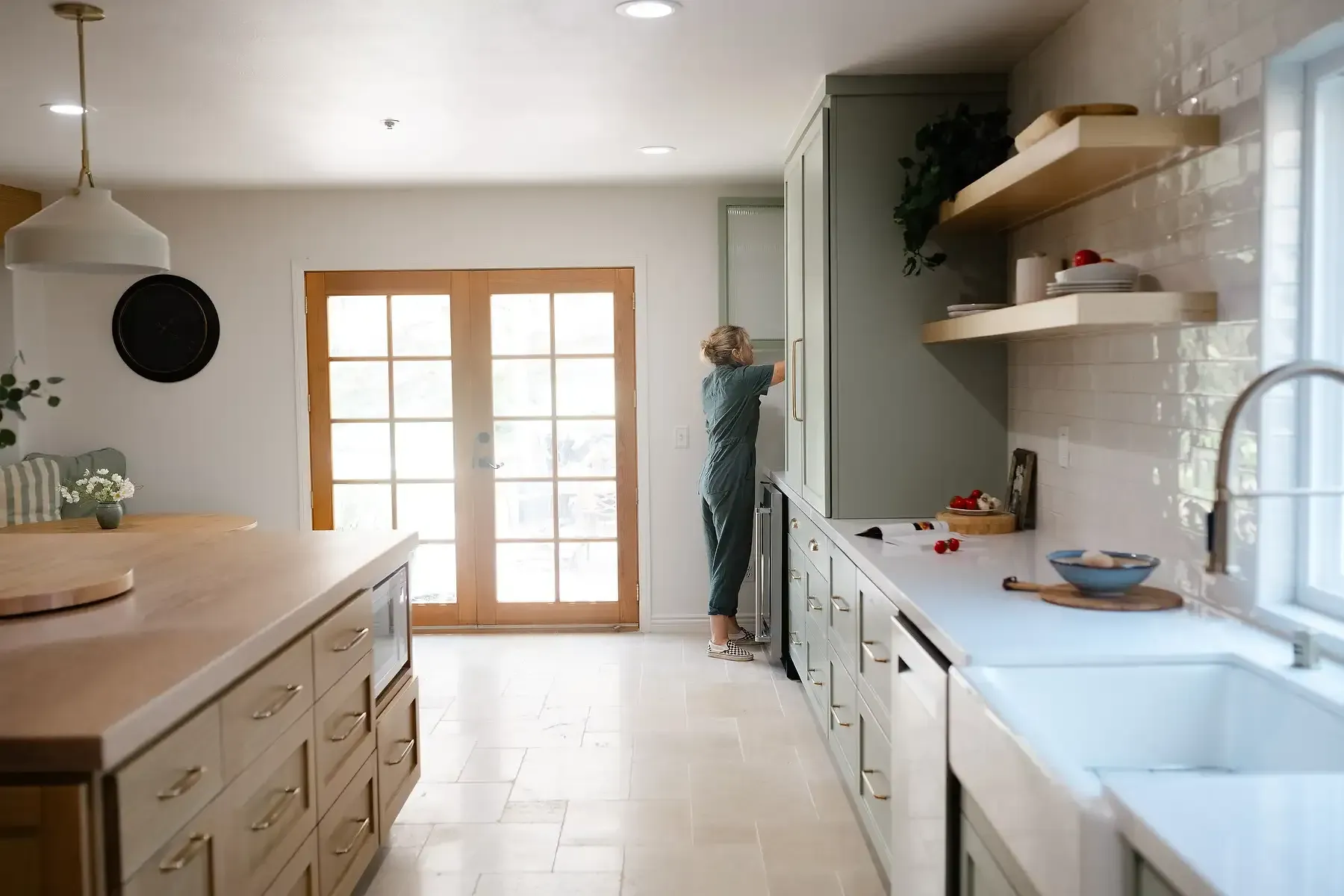 Team Renovate - Person reaching into a green kitchen cabinet in a renovated kitchen