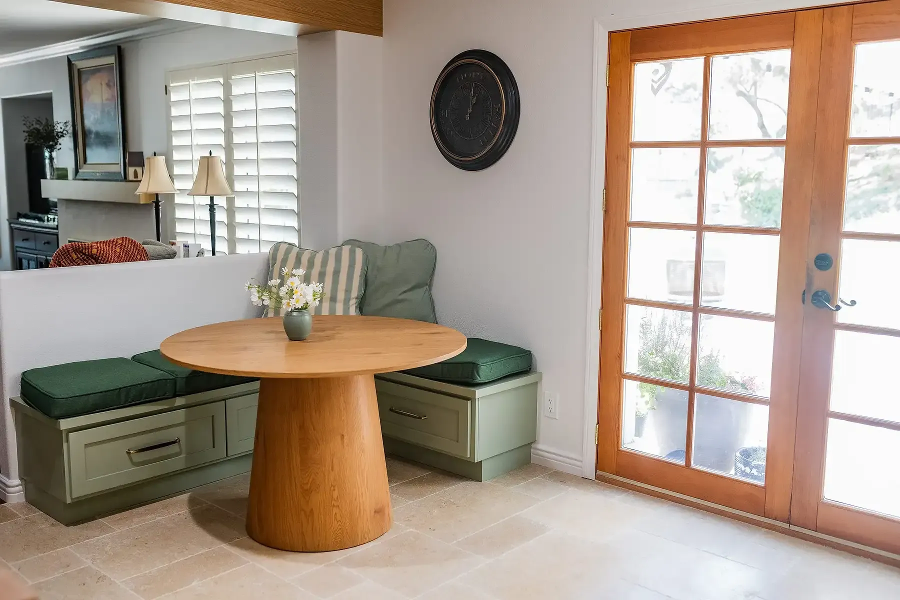 Team Renovate - A small dining nook with a round wooden table, built-in bench seating, and French doors.