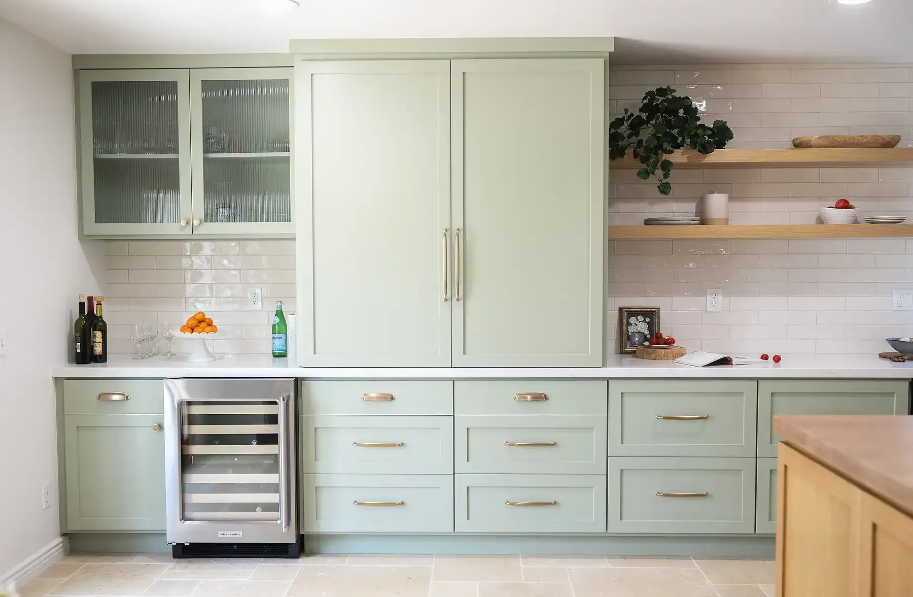 Team Renovate - Green kitchen cabinets with gold hardware and a wine fridge.