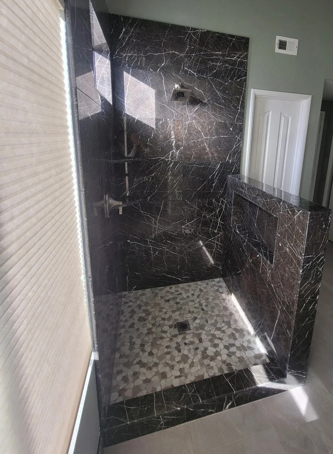 A bathroom with a walk in shower and a window from a Bathroom remodel in San Diego CA by Team Renovate