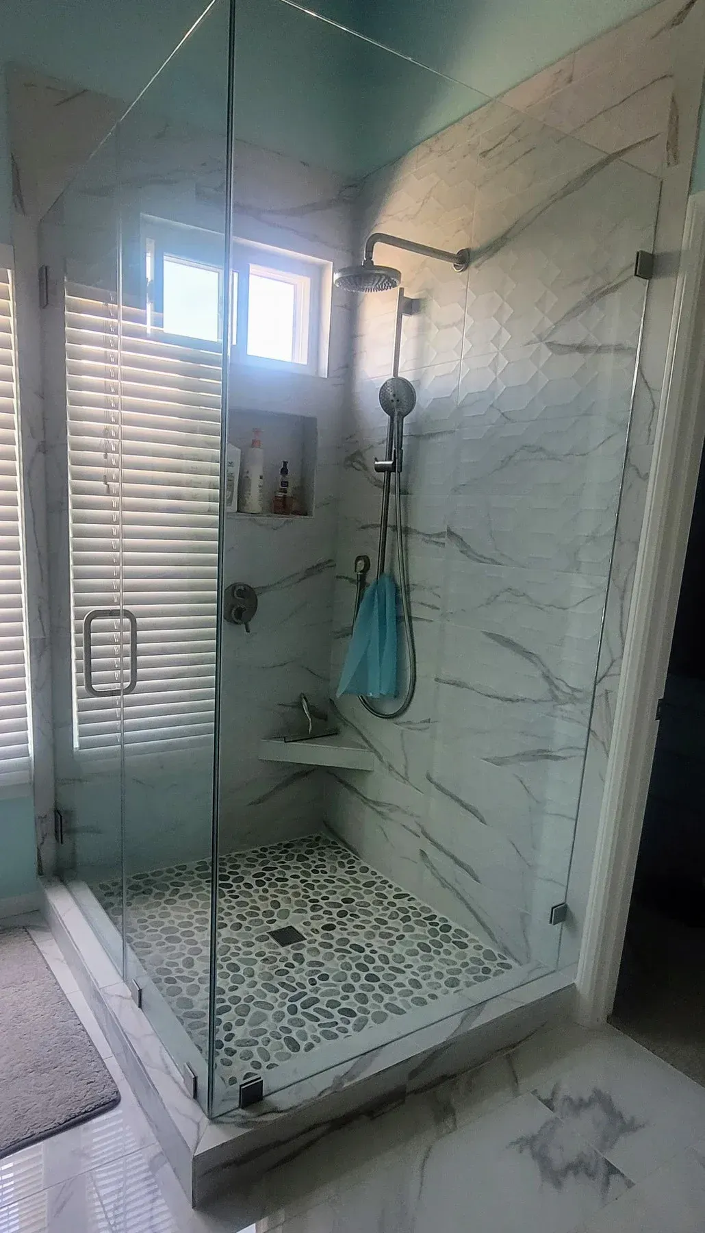 A bathroom with a walk in shower and a window from a Bathroom remodel in San Diego CA by Team Renovate