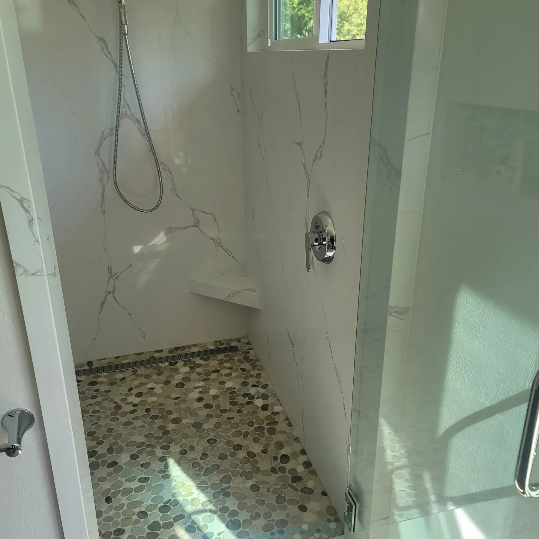 A bathroom with a walk in shower and a window from a Bathroom remodel in San Diego CA by Team Renovate