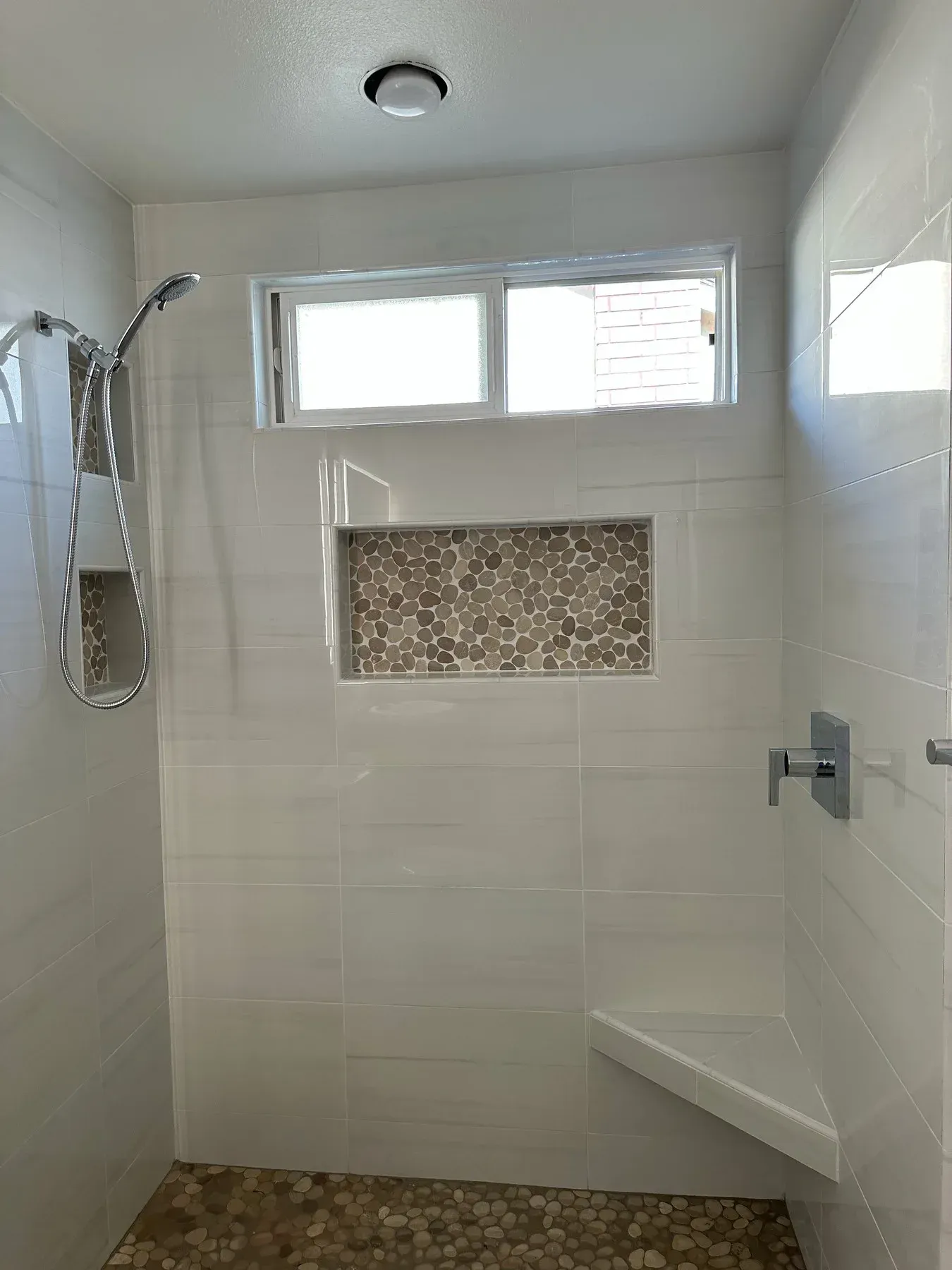 A walk in shower with a window and a bench from a Bathroom remodel in San Diego CA by Team Renovate