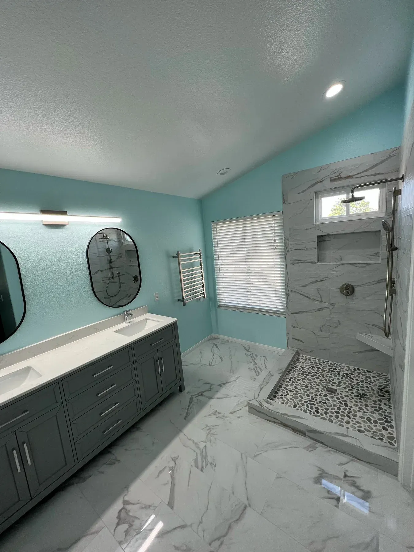 A bathroom with two sinks and a walk in shower from a Bathroom remodel in San Diego CA by Team Renovate