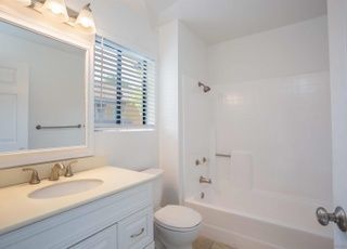 A bathroom with a toilet , sink , mirror and bathtub from a Bathroom remodel in San Diego CA by Team Renovate