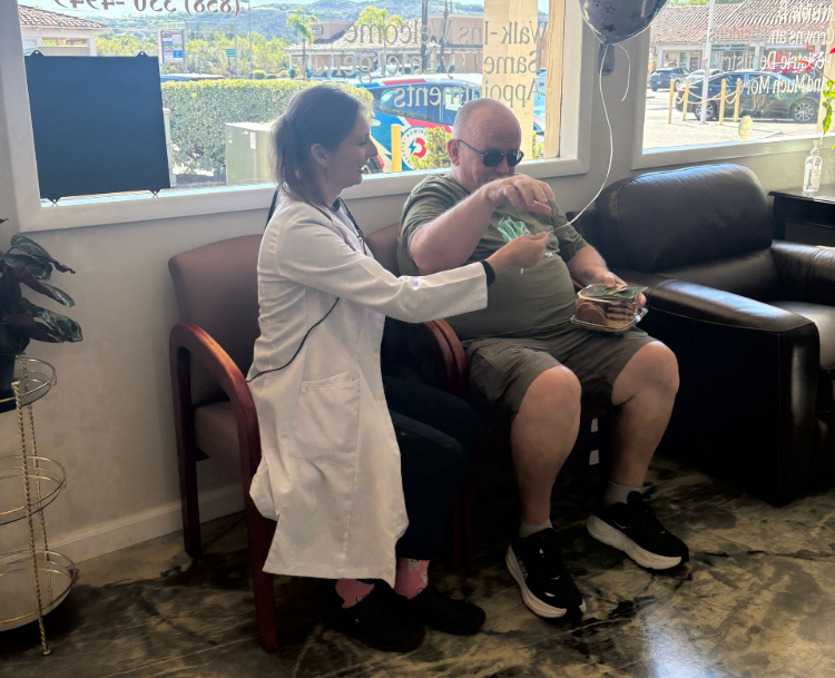 Doctor feeding a seated man in a waiting room beside a window and couch