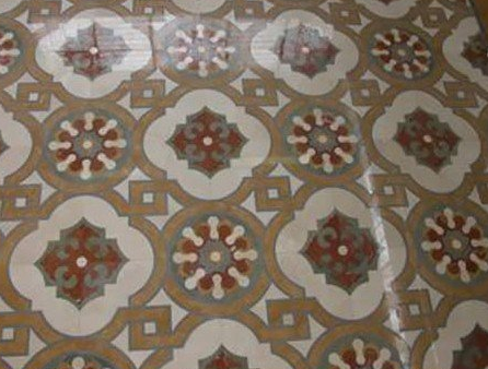 Pavimento in piastrelle decorate con motivi floreali geometrici marroni, bianchi e rossi.