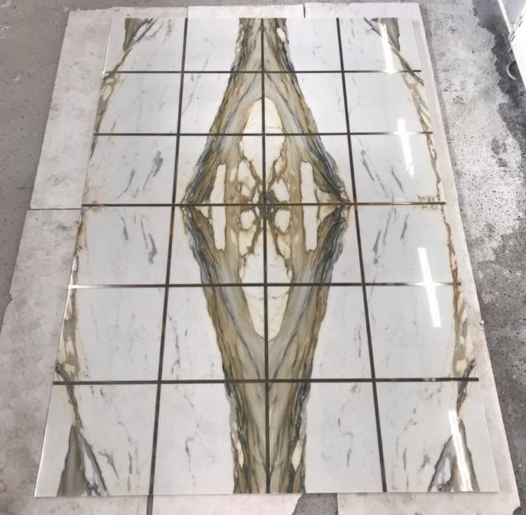 Lastra di marmo bianco con venature grigie e dorate, centrata su un pavimento con fughe.