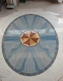 Mosaico pavimentale circolare blu e grigio con un piccolo medaglione a forma di stella multicolore al centro.