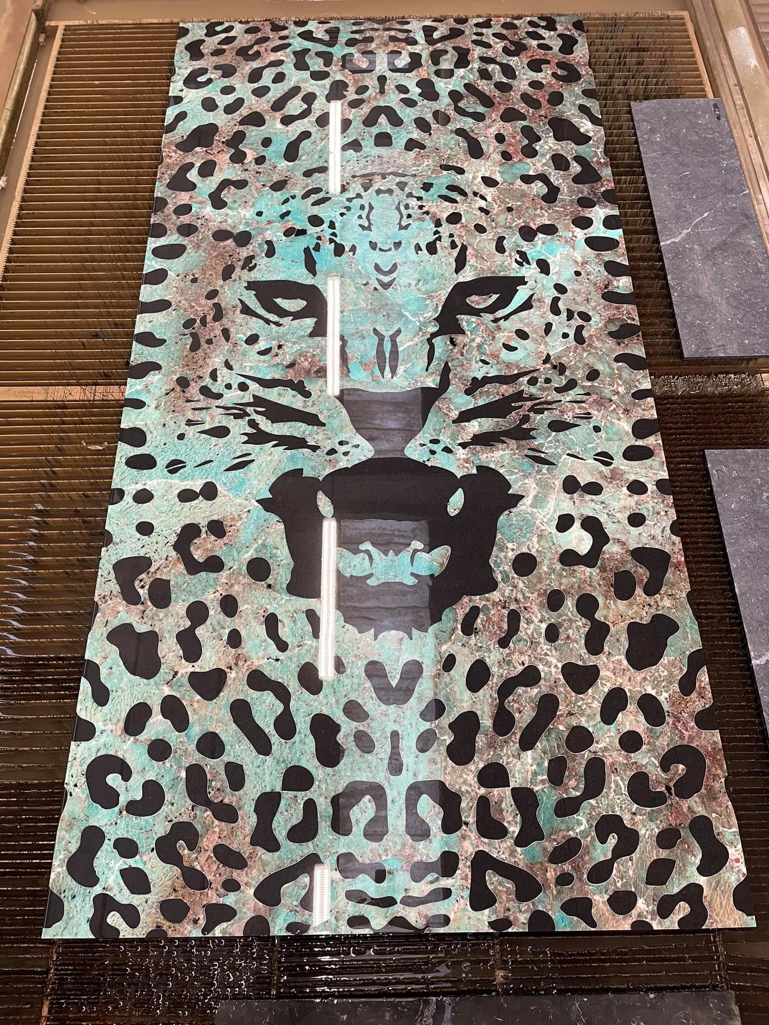 Tappeto con stampa leopardata a forma di muso di tigre su pavimento in legno, con bocca centrale scura e dettagli color verde acqua.
