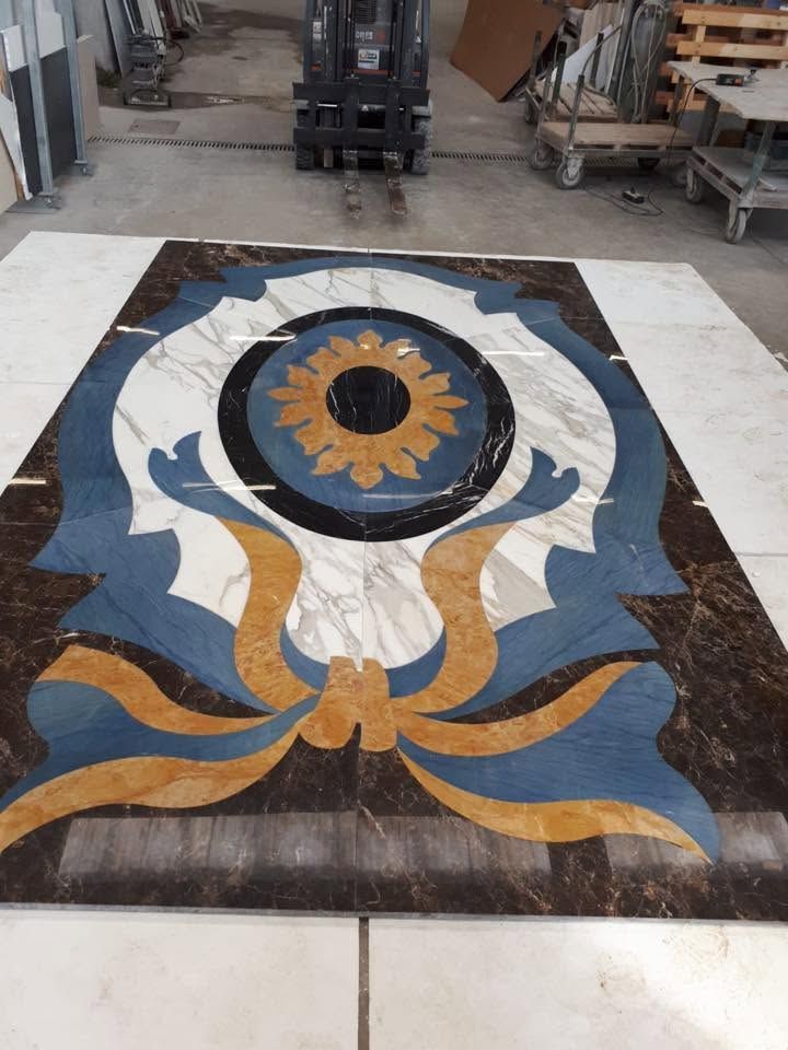 Pannello decorativo a mosaico per pavimento con motivo floreale blu, bianco, oro e nero in un ambiente adibito a laboratorio.