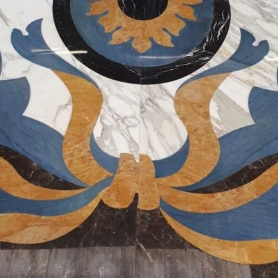 Mosaico ornamentale per pavimento nei toni del blu, oro e nero, con motivo floreale simmetrico su marmo bianco.