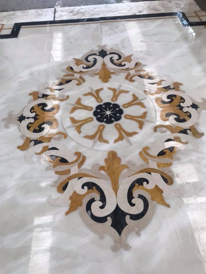 Elegante medaglione floreale in oro, nero e bianco su un pavimento in marmo lucido.