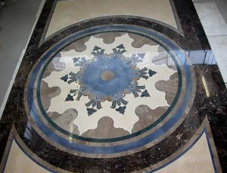 Medaglione circolare a mosaico per pavimento, con motivo floreale blu e bianco, bordato da piastrelle di marmo nero.