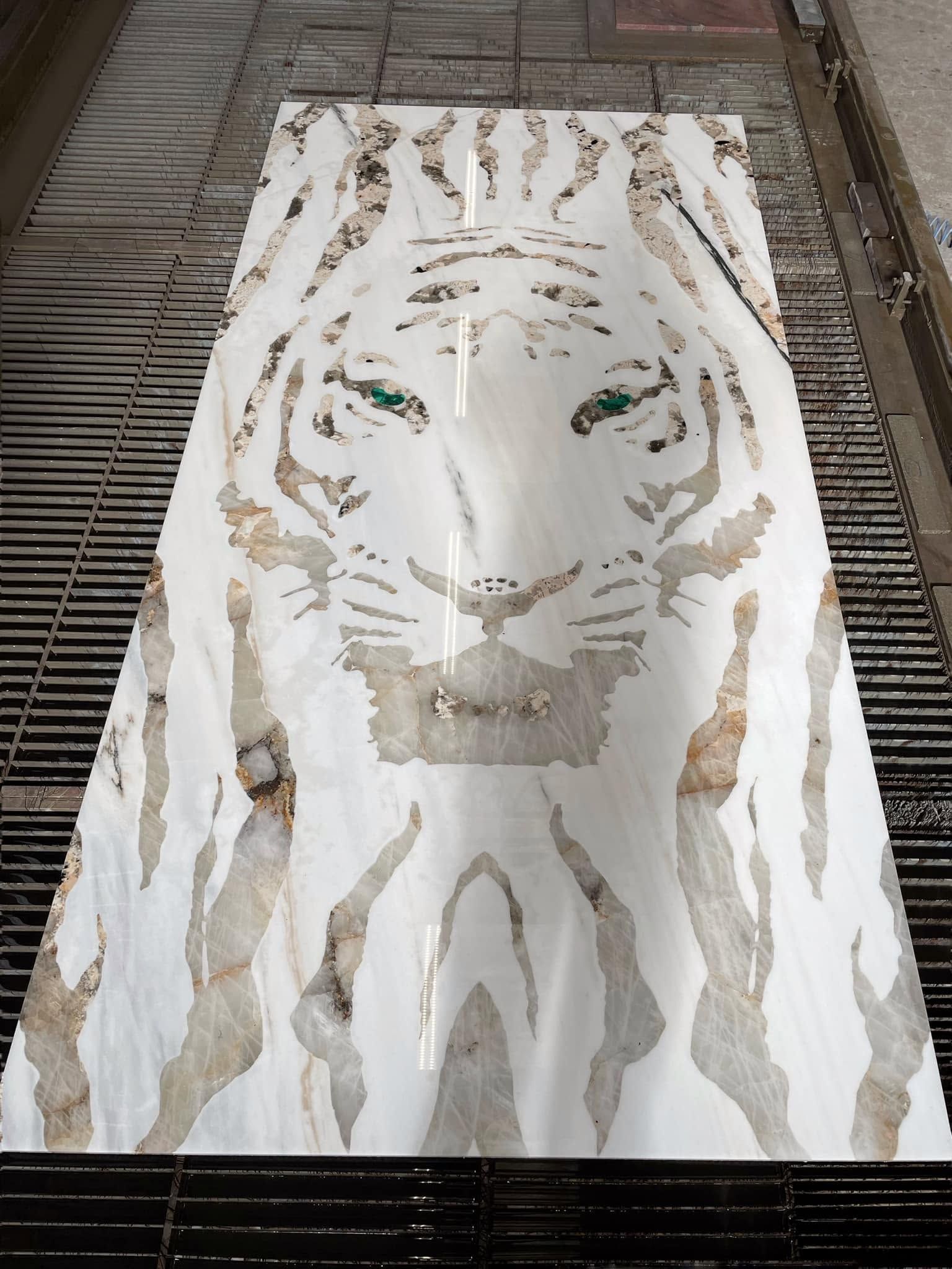 Un'opera d'arte raffigurante il volto di una tigre bianca su un foglio rettangolare posato su un vialetto di mattoni.