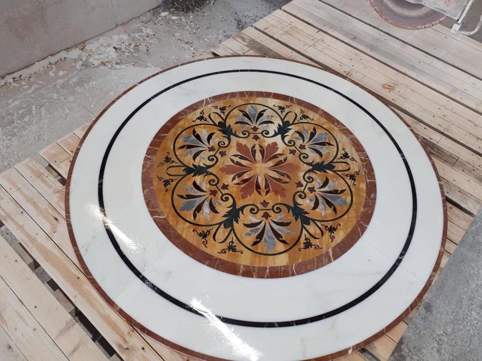 Piatto rotondo bianco con un centro decorativo floreale e geometrico marrone su un tavolo di legno.